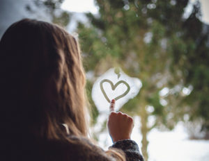 petite fille qui écrit sur vitre avec la buée